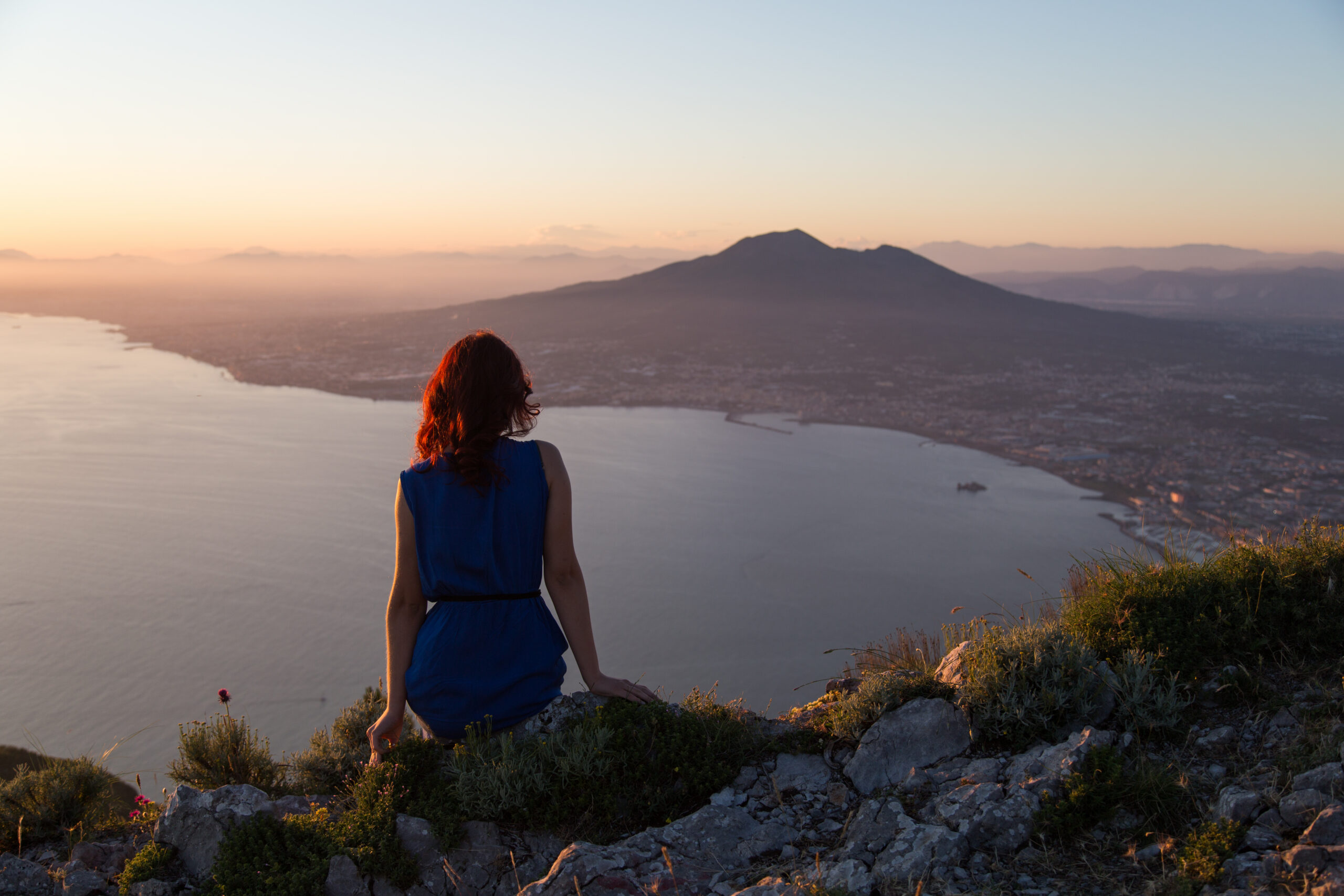 girl-sits-background-entire-gulf-naples-volcano-vesuvius-sunset