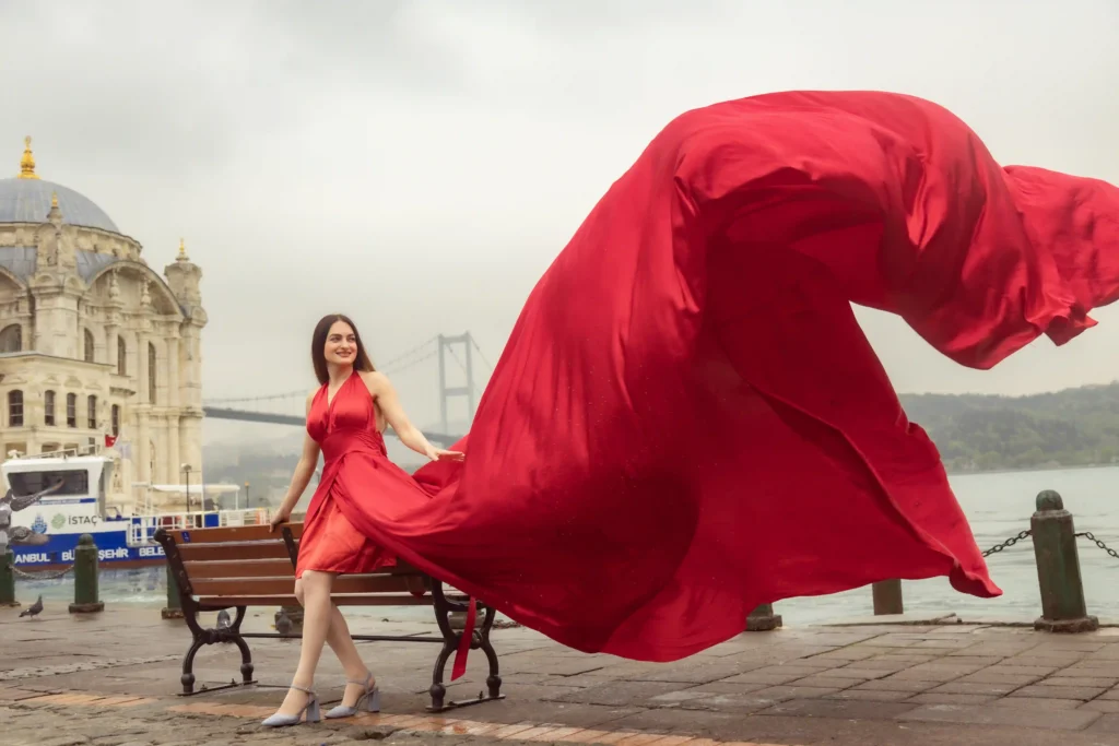 Woman in a flying red dress by the Bosphorus at Ortaköy Mosque with the Bosphorus Bridge in Istanbul, Turkey.