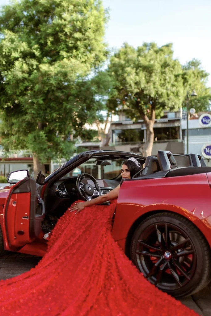 Bride in a red gown stepping out of a red convertible in Ortaköy, Istanbul, for a luxury wedding photoshoot.