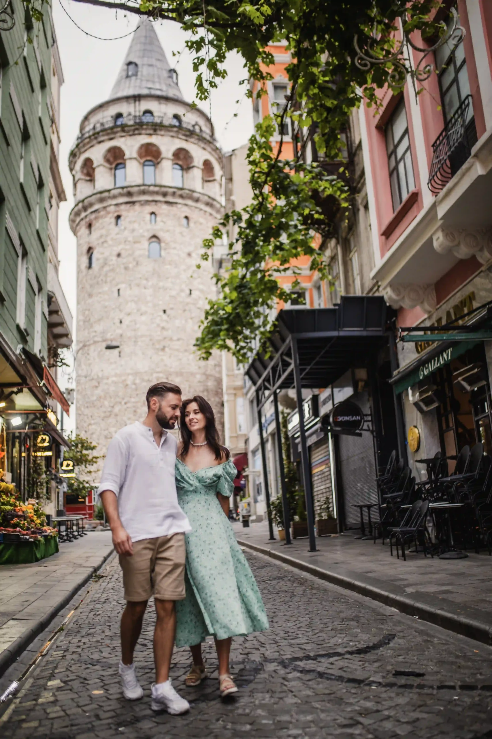 Couple strolling through a Galata street with Galata tower behind