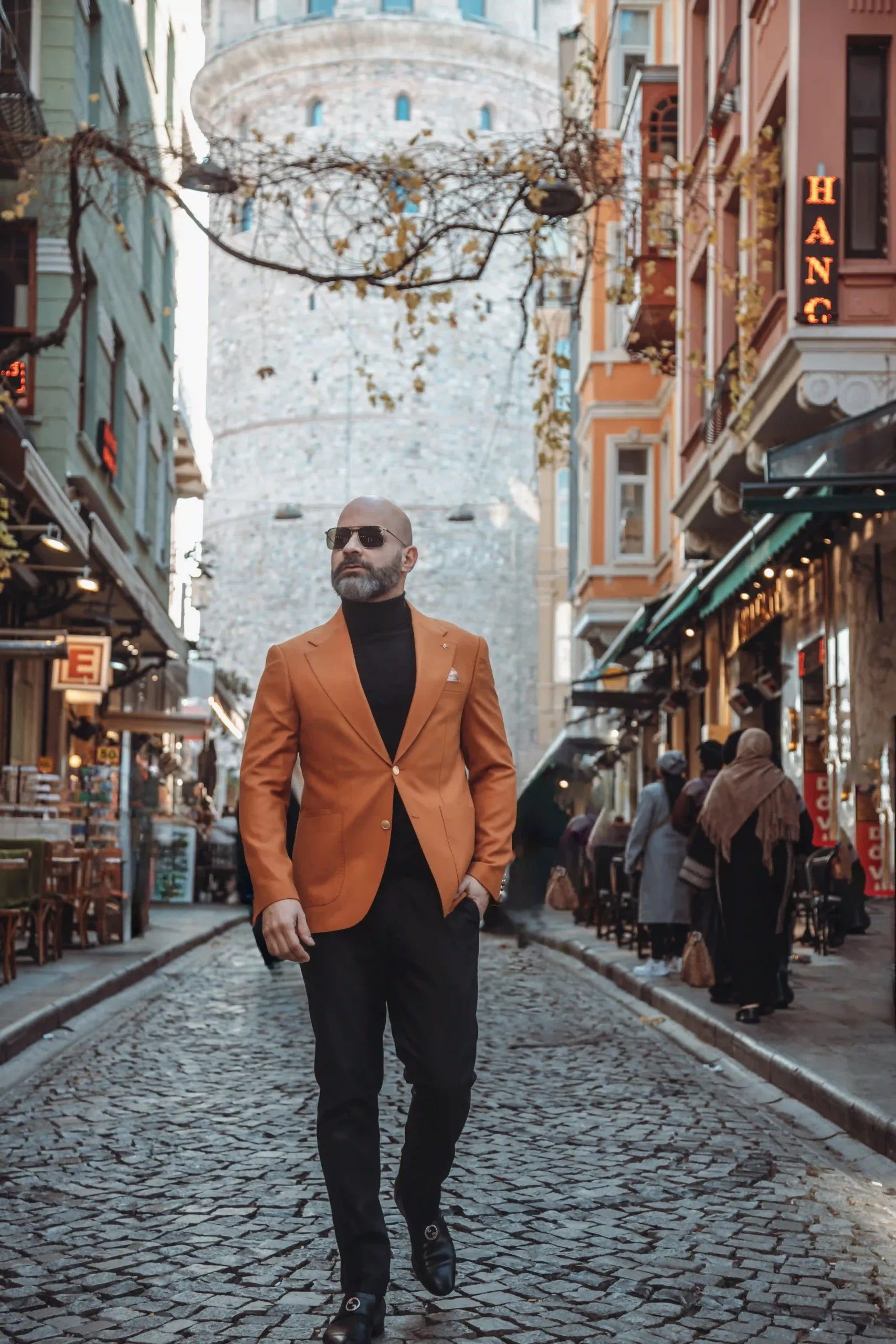 man in orange blazer waking through a cobblestone street in Galata