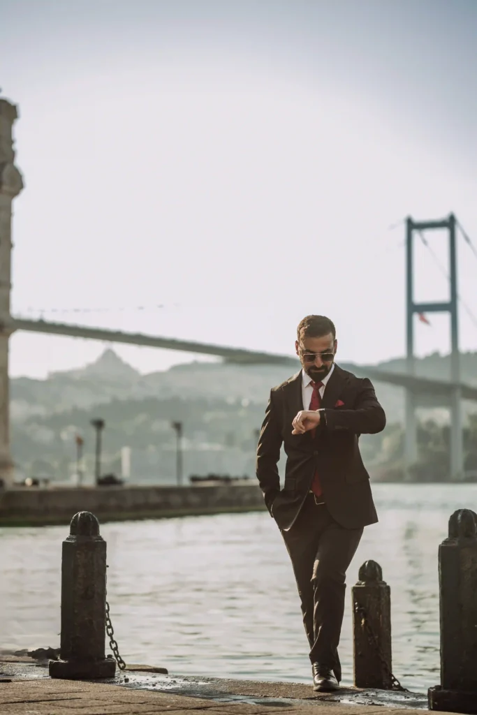 Man in suit checking his watch by the Bosphorus with Bosphorus Bridge in the background, Ortaköy Istanbul