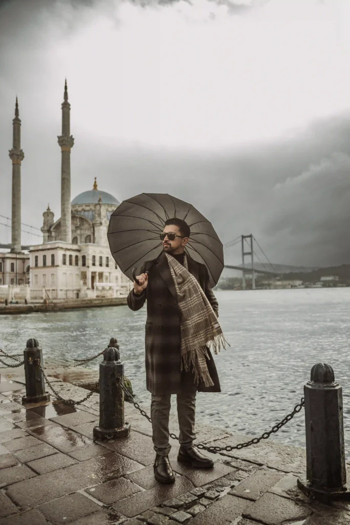 male poses in Istanbul, stylish man with umbrella on a rainy day at Ortaköy Mosque and Bosphorus Bridge