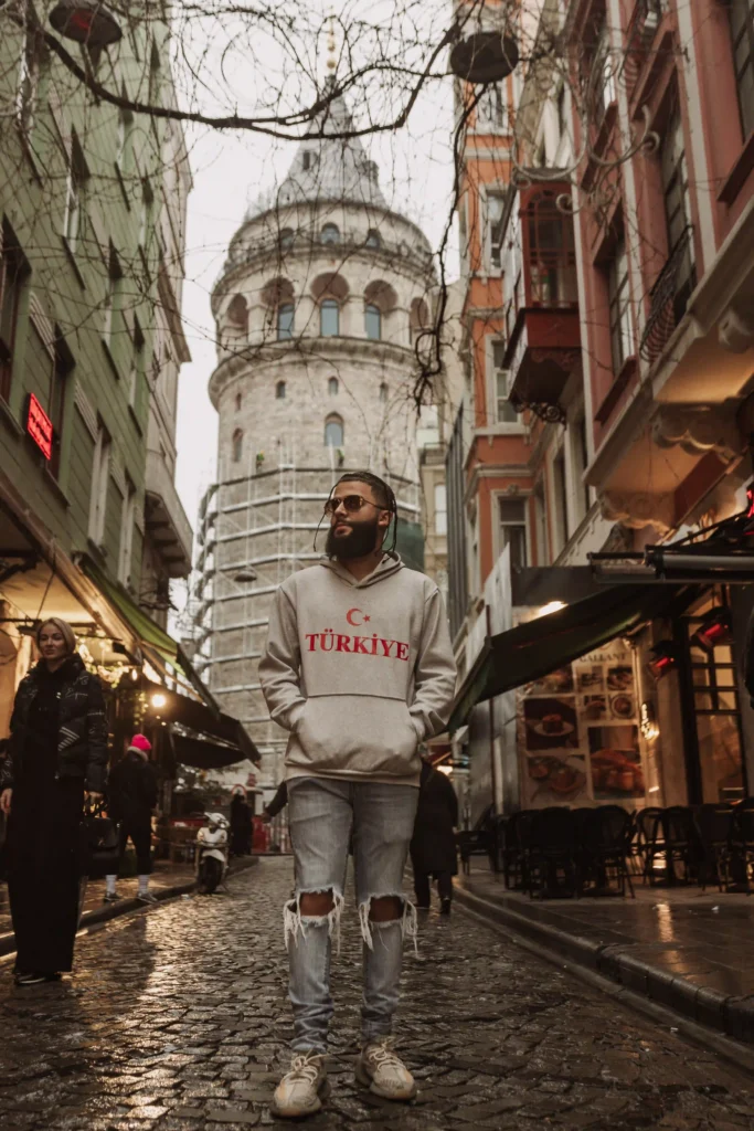 A simple male poses in Istanbul/ A man in a hoodie around the Galata Tower